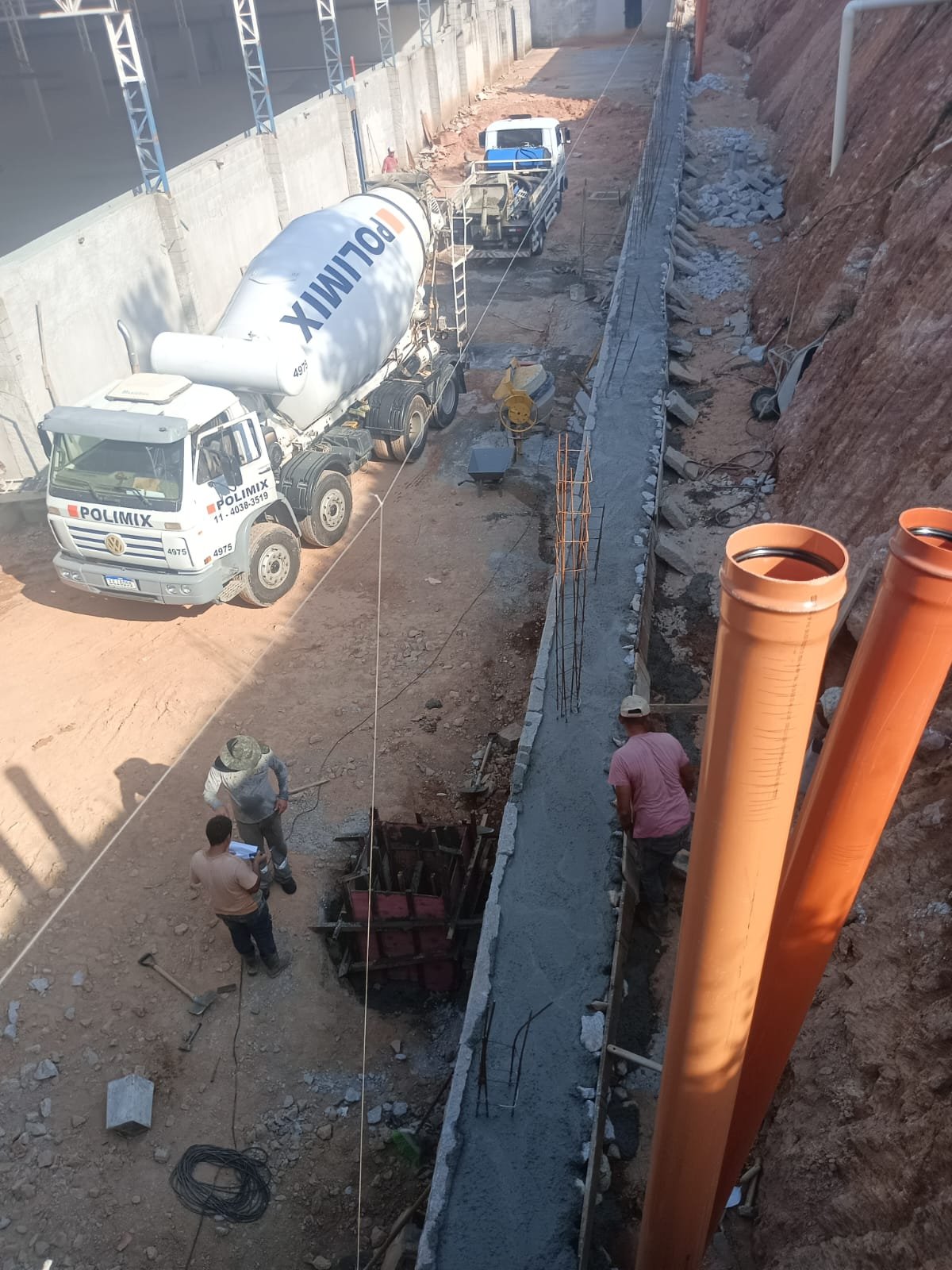 Obra em andamento com caminhão betoneira e tubulação instalada