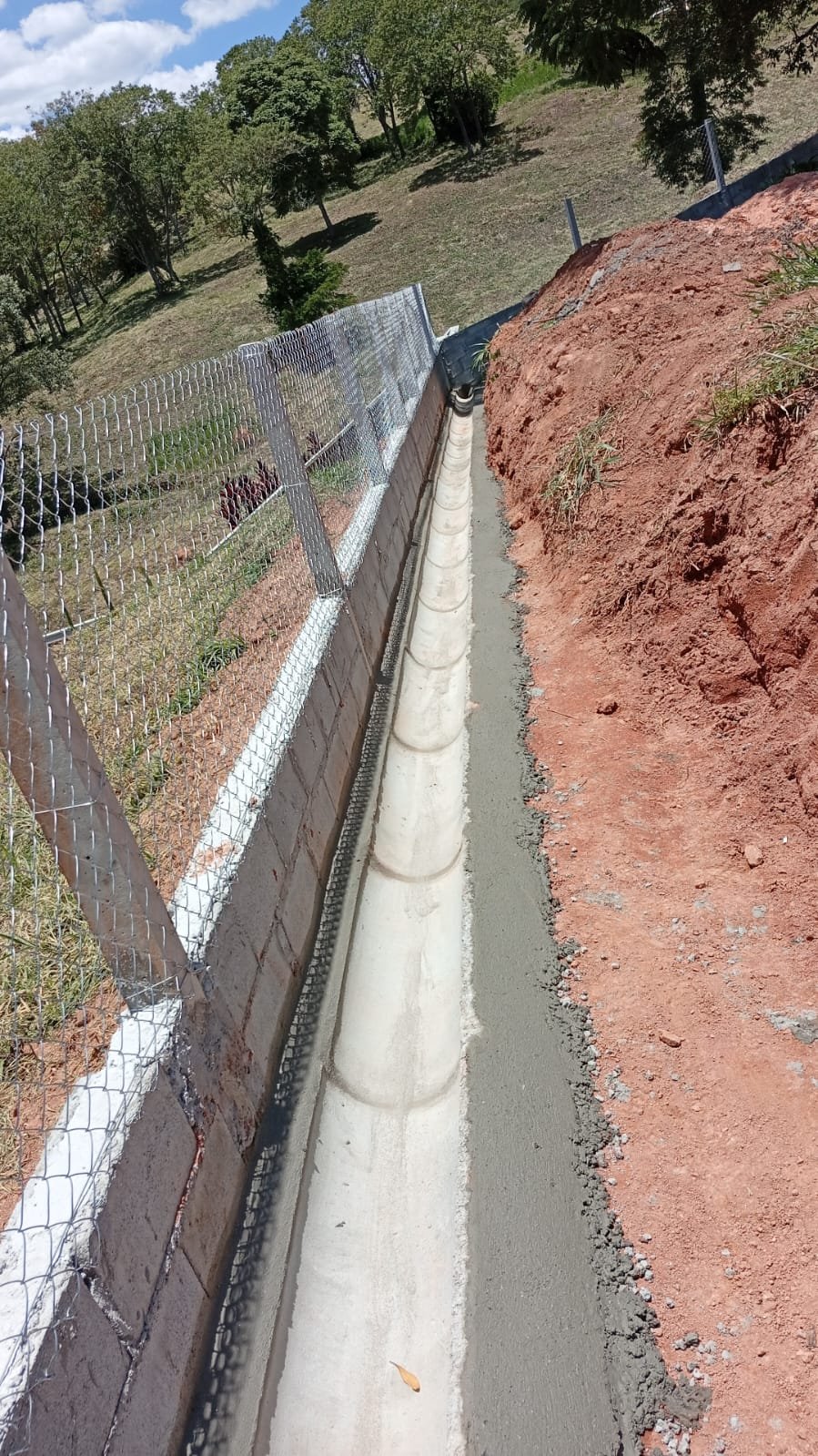 Canaleta de concreto com tubulação assentada em terreno inclinado