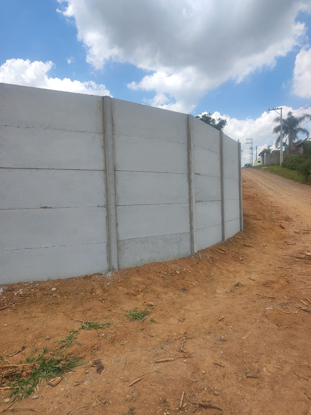 Muro pré-moldado em curva com vista de estrada de terra